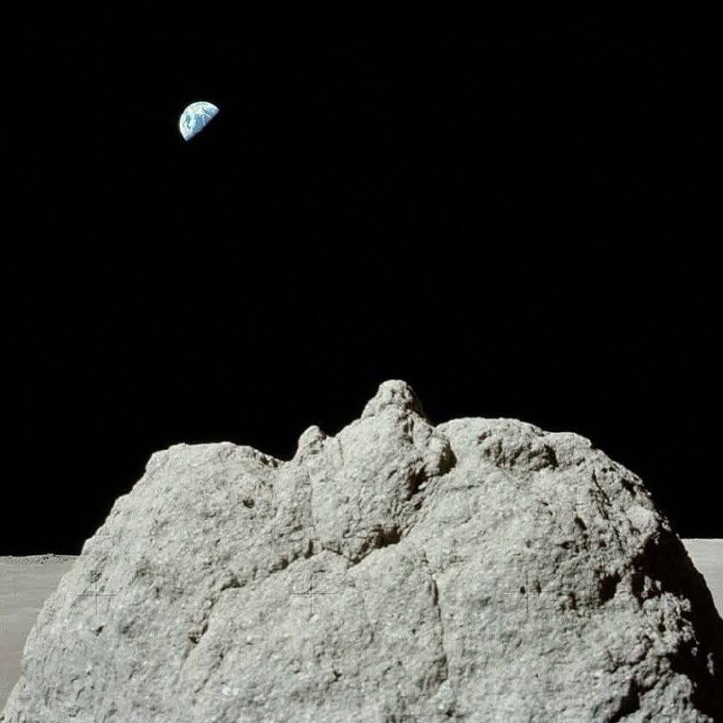 Beautiful Earth (the "blue marble") above the gray lunar rocks.